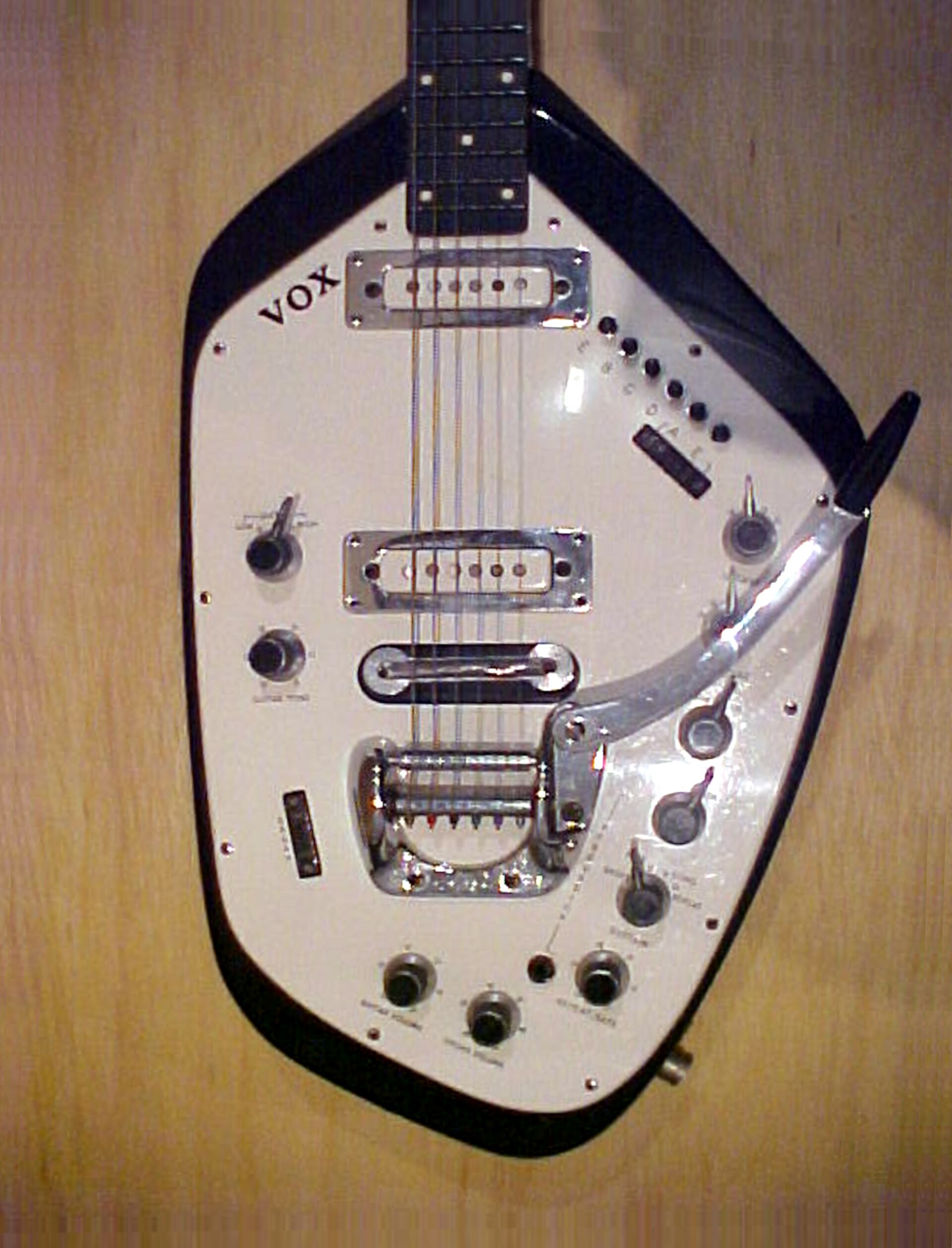 Body of a Vox Guitar Organ in black and white, with organ voice switches and controls on the white pickguard and a tremolo arm